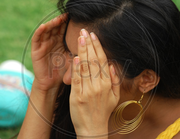 An Indian woman covering her face with hands