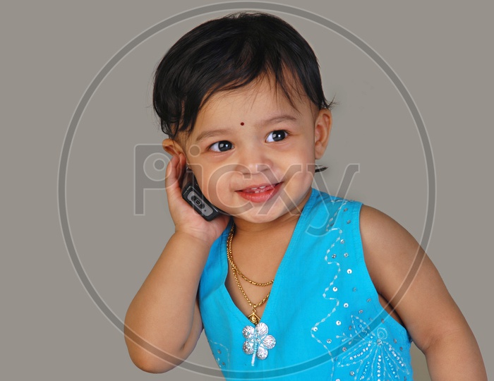 Baby girl in blue frock with a mobile phone