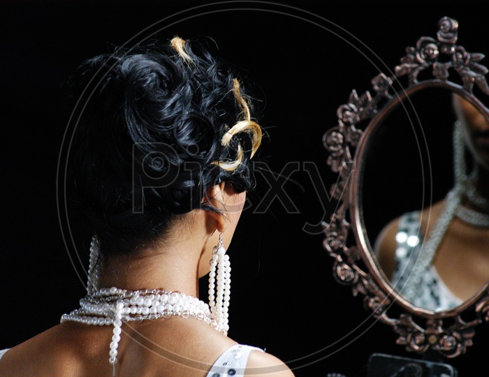 Indian woman wearing pearl necklace looking in the mirror
