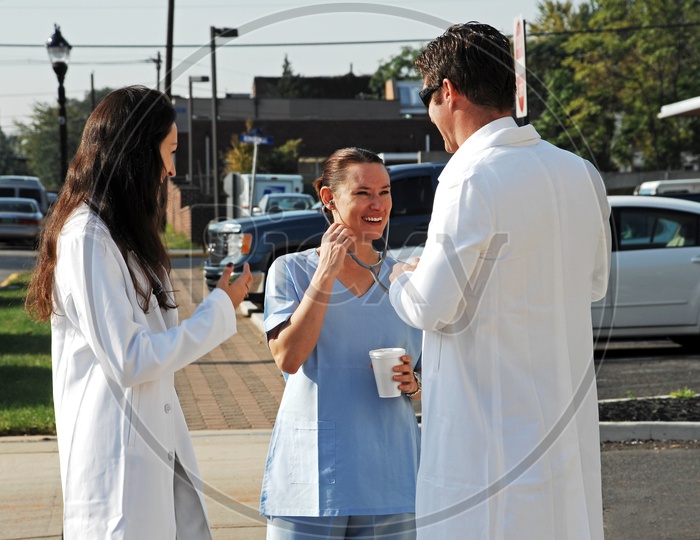 Young male and female doctors with a female nurse laughing on the road