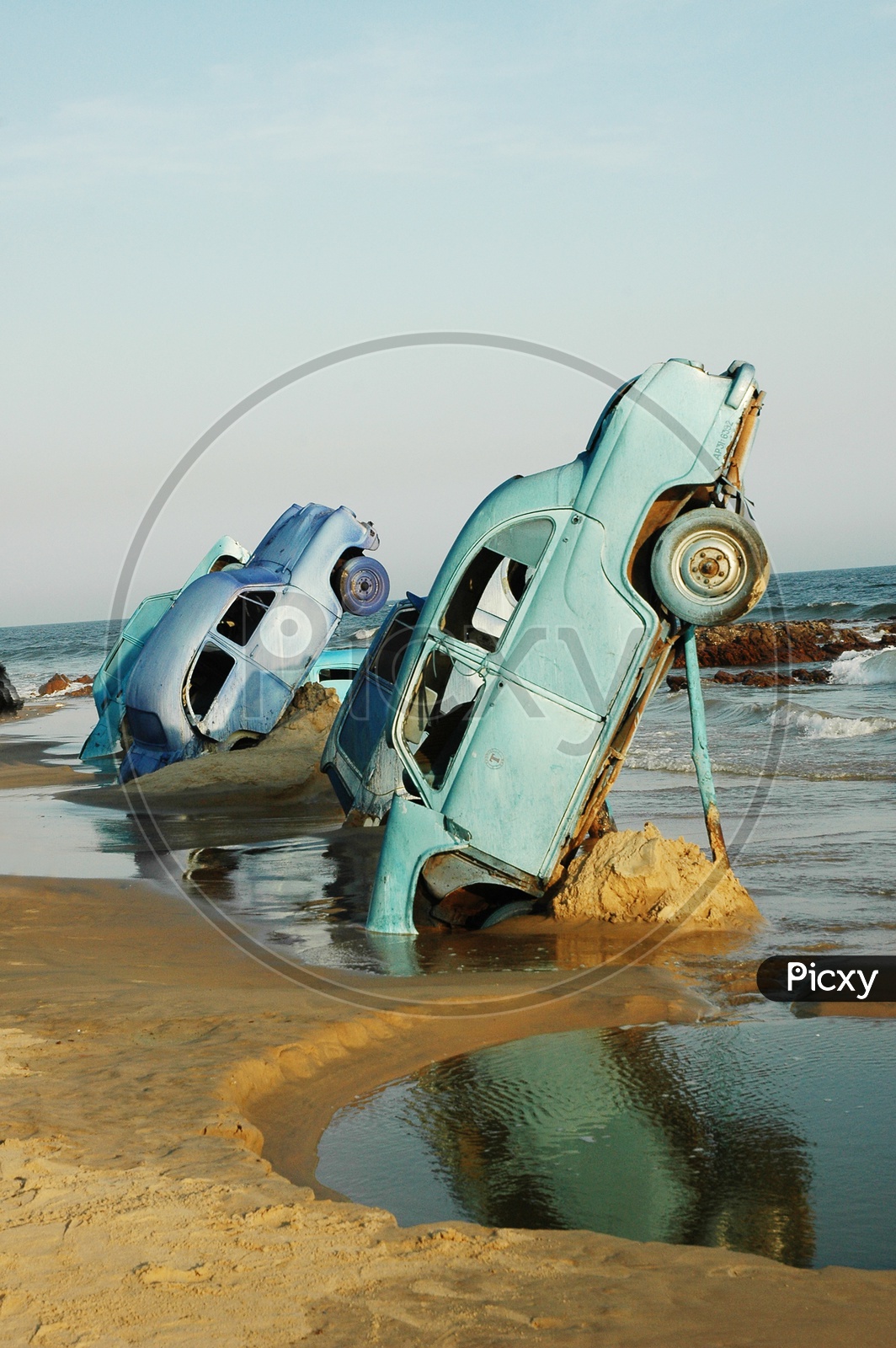 An old blue cars stuck in the sand at the beach
