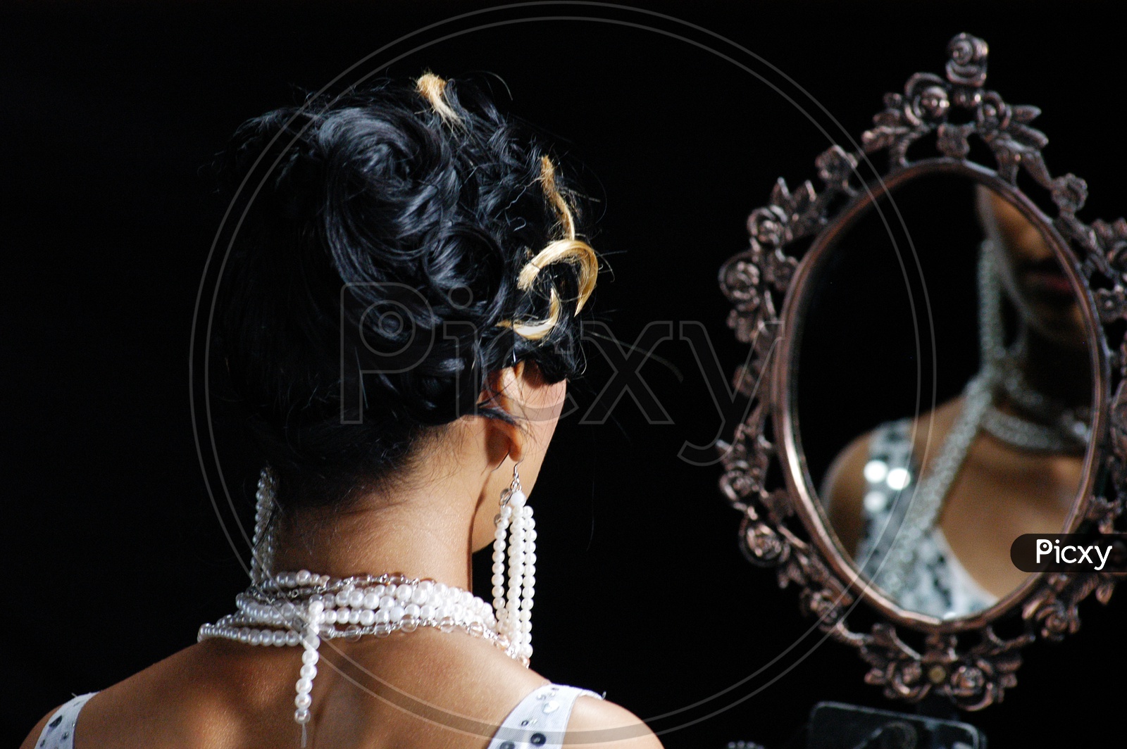 Indian woman wearing pearl necklace looking in the mirror