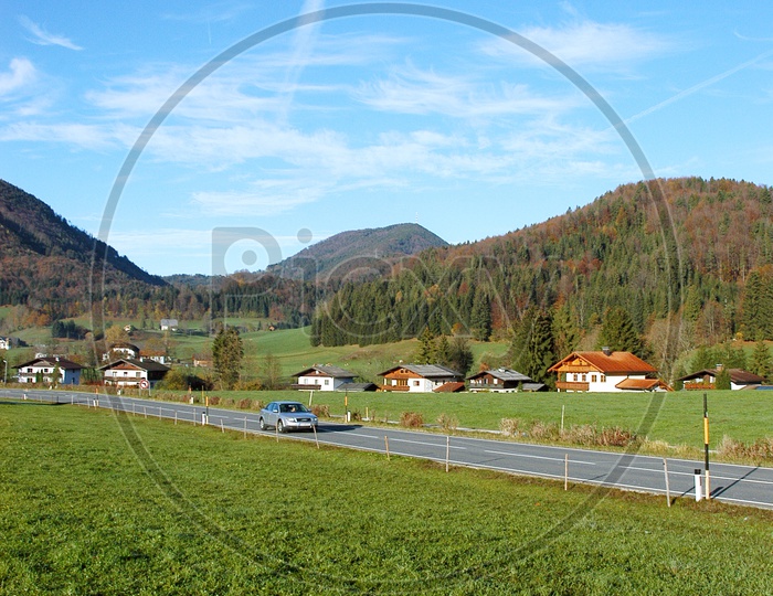 Roadway alongside the green meadow and Alpines
