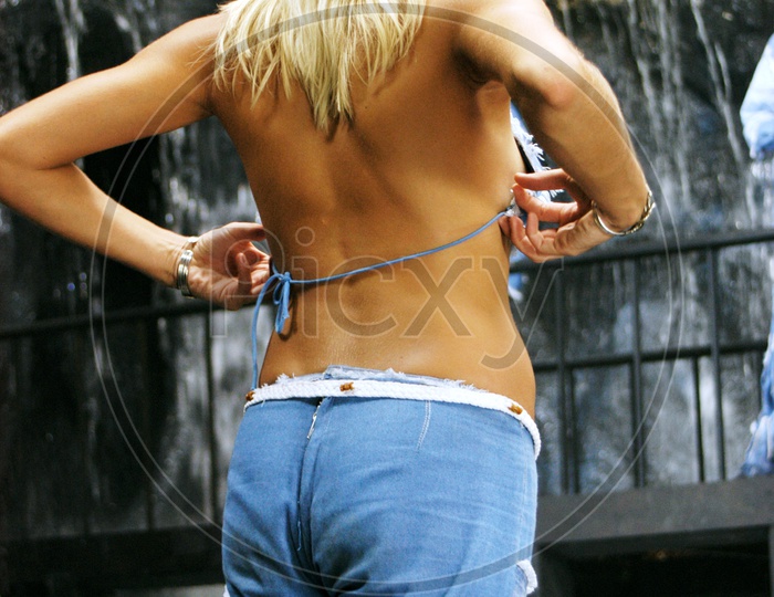 A female model with backless top and blue torn jeans