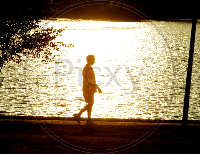 A man going for a walk by the lake during the golden hour