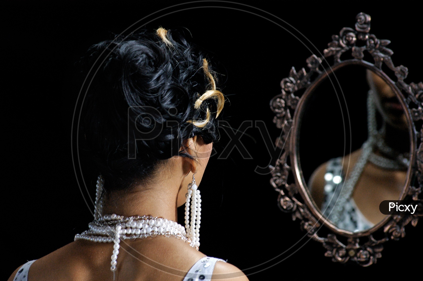 An Indian Woman wearing pearl necklace looking in mirror