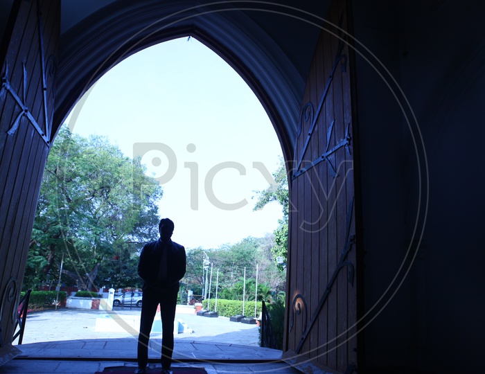 Silhouette of a Man Standing at a Church Entrance Door