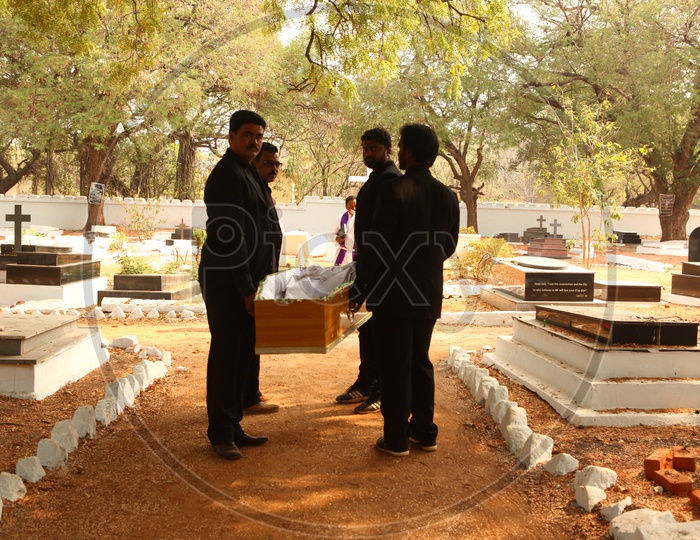 Men Dressed In Black Carrying a Coffin Box Or Funeral Box