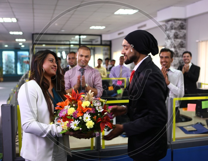 Office Staff Welcoming Young Lady Boss Into Office With a Flower bouquet
