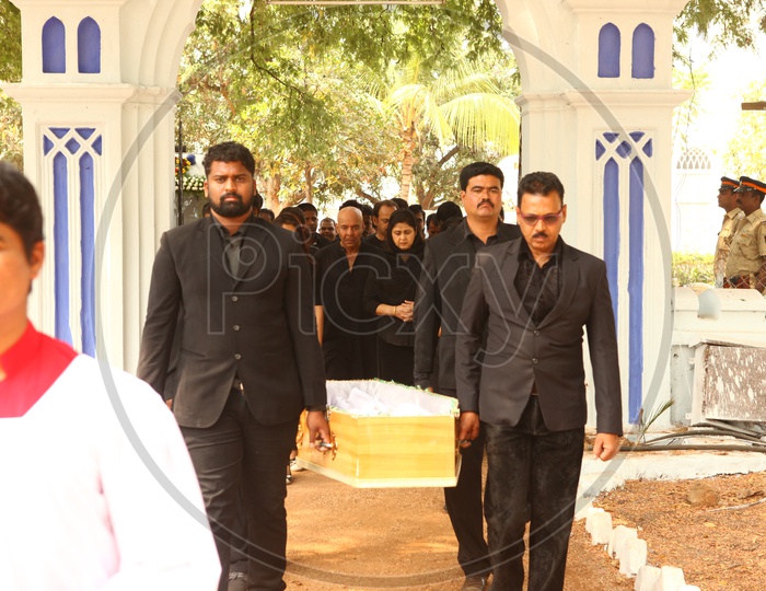Men Dressed In Black Suits Carrying Funeral Box Or Coffin Box To Crematorium