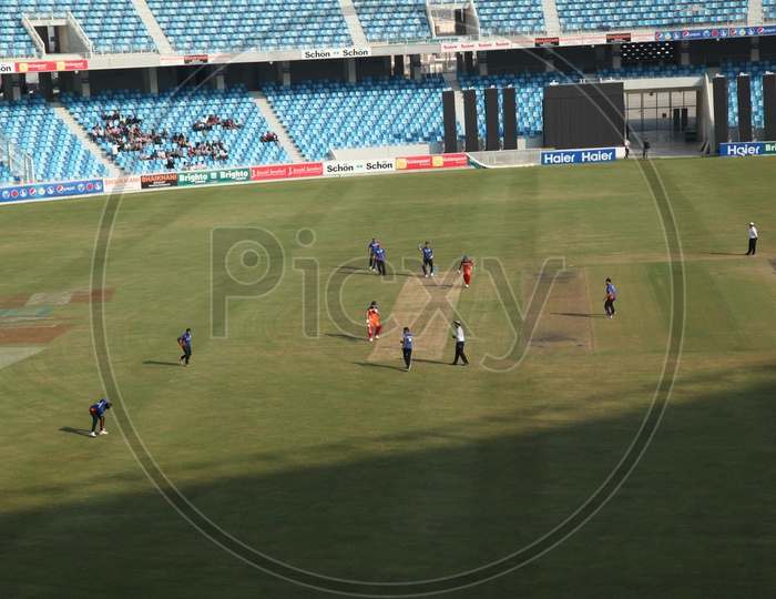 Cricketers Playing Cricket In a  Stadium