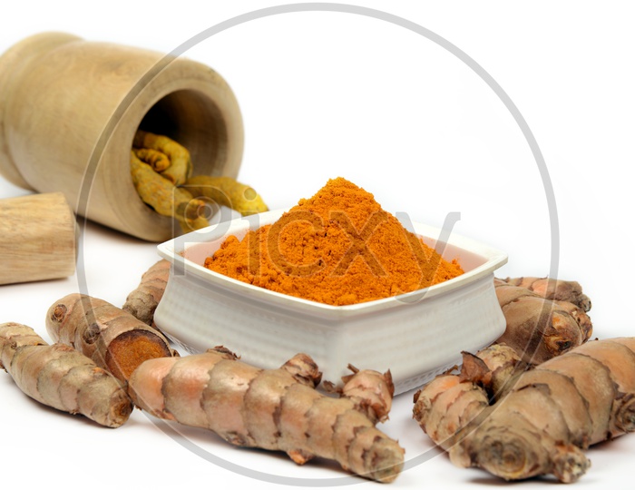 Organic Turmeric roots and Turmeric Powder in a bowl and wooden mortar, Indian spices