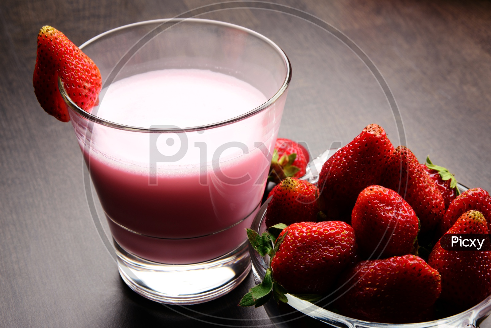 Fresh Strawberry milk shake in a glass with fresh and ripe strawberry in a bowl