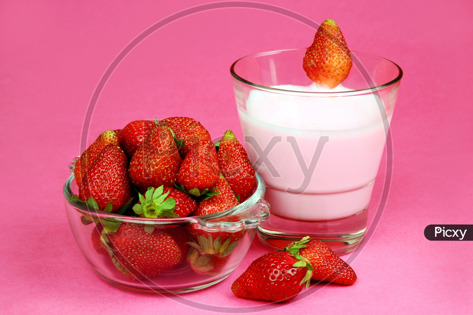 Fresh Strawberry milk shake in a glass with fresh and ripe strawberry in a bowl
