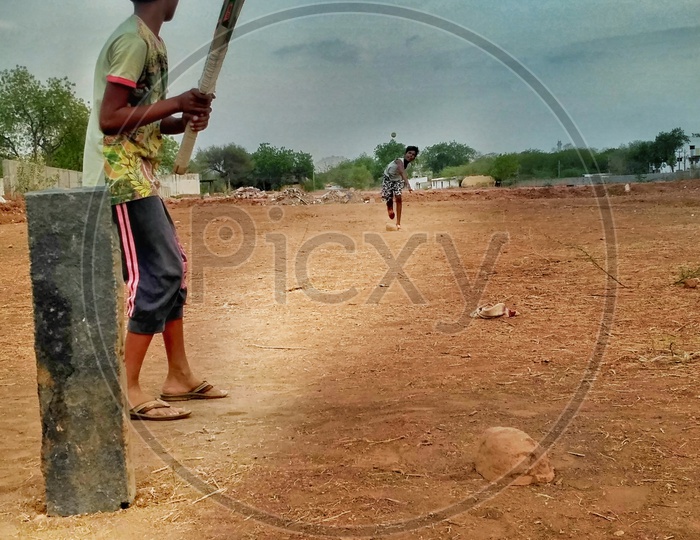 Two kids playing rural cricket