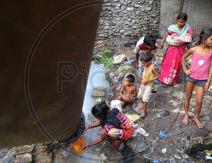 Slum Area People  Filling Peeping Out Water  From  Pipe lines