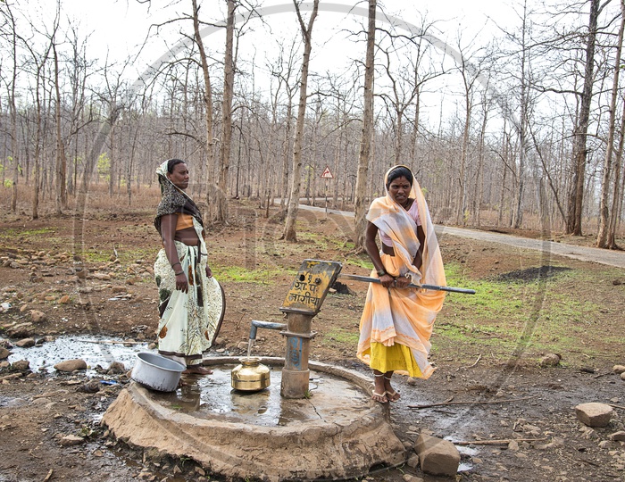 Unidentified rural Indian women carry water on their heads in traditional pots from hand pump, everyday Women walk few kilometers to get it due to drought.