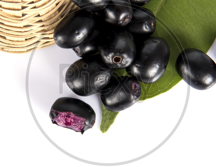 Jambolan plum or Java plum (Syzygium cumini) or Berry  Fruit In a Wooden Weaved Basket On an Isolated White Background