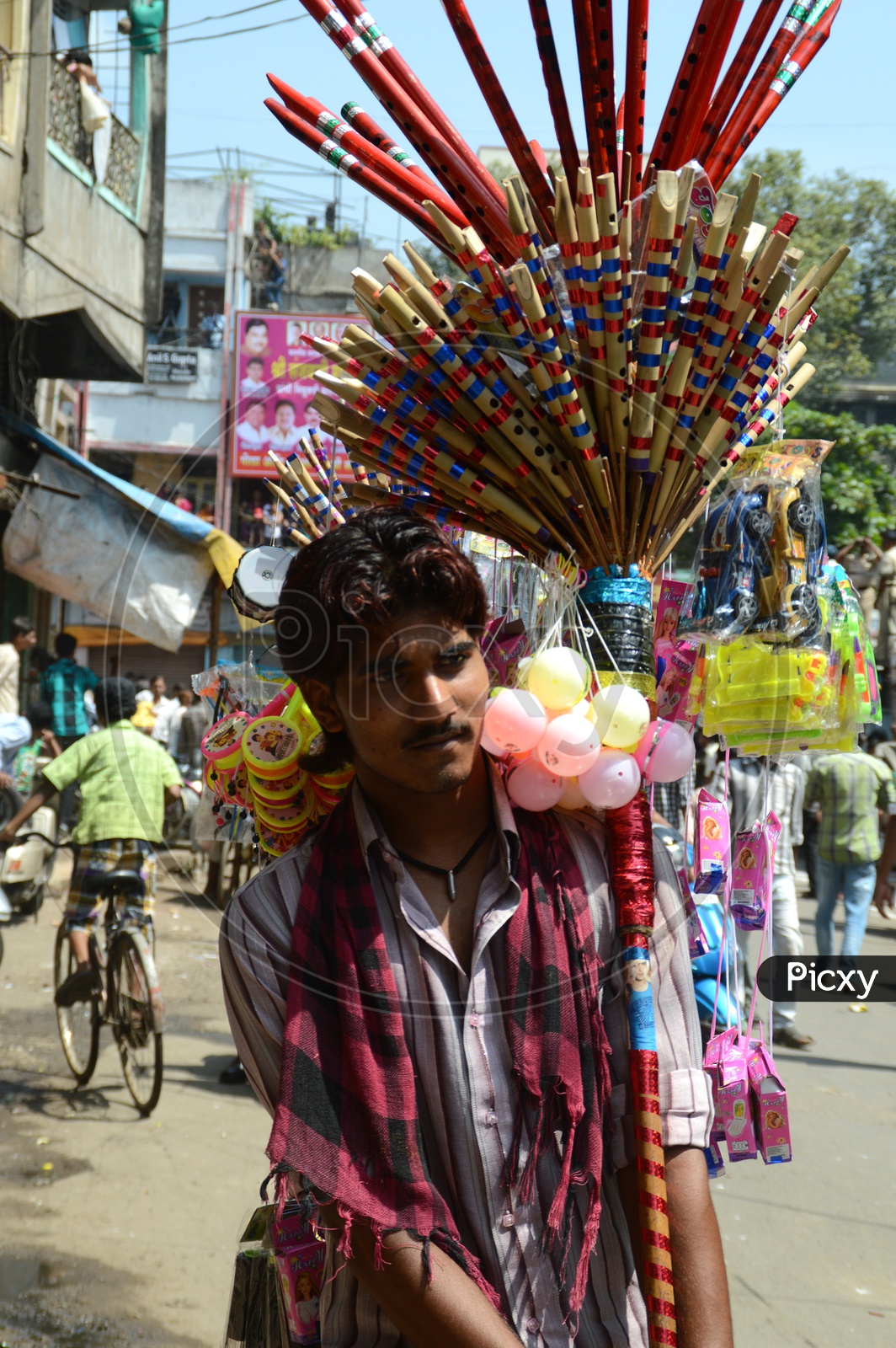 A Flute Vendor On The Streets Carrying On His Shoulder