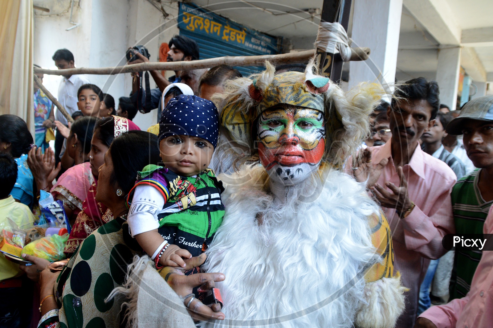 A Man Dressed Up Like Lion And Holding a Child In Hands in Marbat Procession