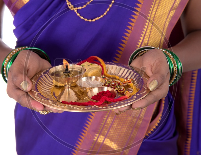 Portrait Of a Beautiful Young Girl Wearing Traditional Saree and holding Pooja Thali Or Plate For  Performing Worship on an Isolated White Background