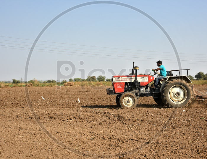 An Indian Farmer Ploughing The Agricultural Field With Tractor Preparing The Land For Sowing With Seedbed Cultivator