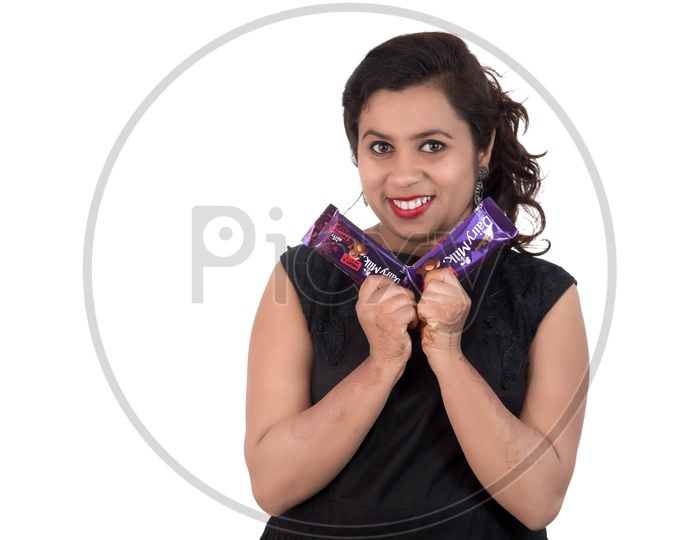 A Pretty Young Beautiful Woman Holding Diary Milk Chocolates In Hand And Smiling On an Isolated White Background