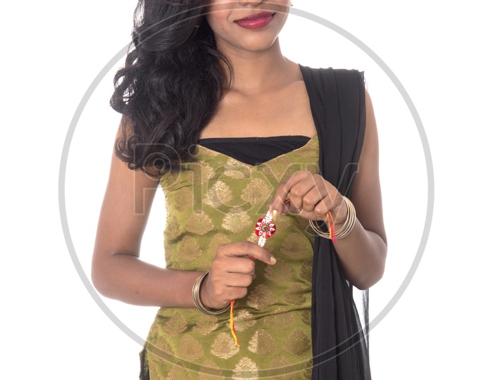 A Beautiful Young Indian Girl Holding An Elegant Rakhi in Hand  and Posing On an isolated White Background