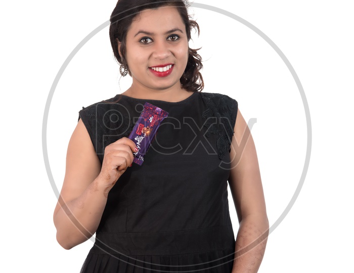 A Pretty Young Beautiful Woman Holding Diary Milk Chocolates In Hand And Smiling On an Isolated White Background