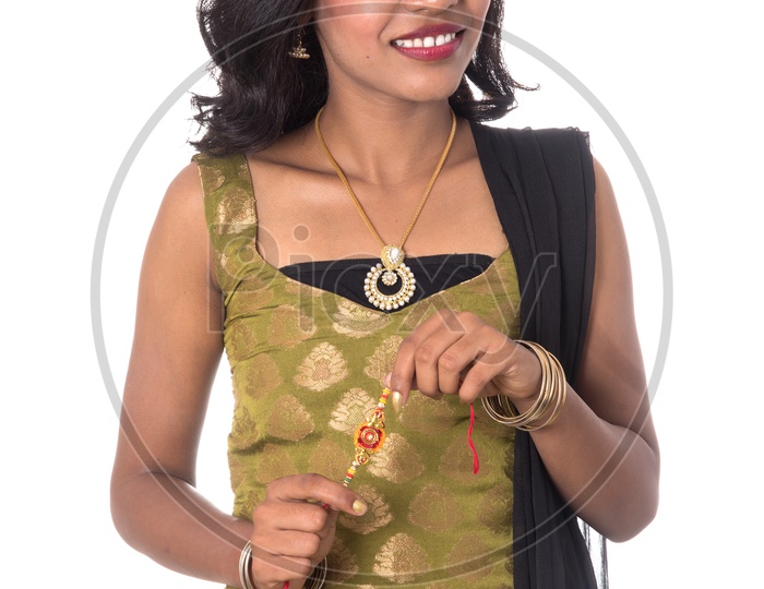 A Beautiful Young Indian Girl Holding An Elegant Rakhi in Hand  and Posing On an isolated White Background
