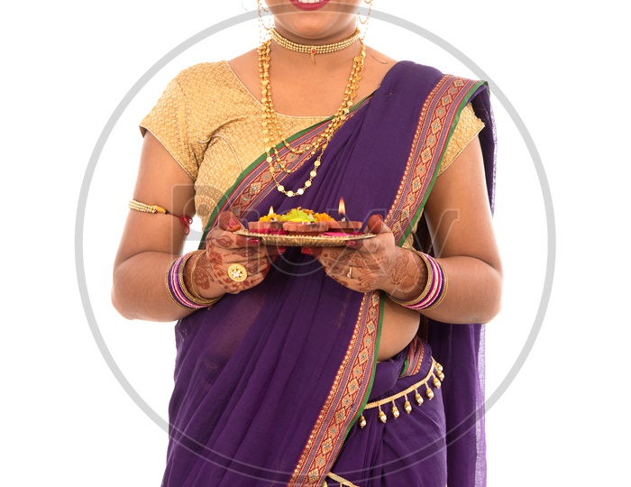 A Traditional Indian Marathi  Woman  Holding Diwali Diyas on an  Pooja Plate   In Hand  and Posing  On an Isolated White Background