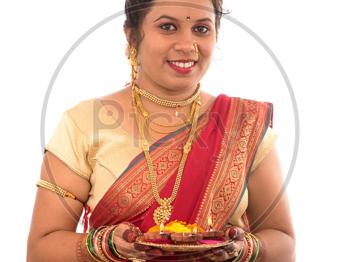 A Traditional Indian Marathi  Woman  Holding Diwali Diyas on an  Pooja Plate   In Hand  On an Isolated White Background