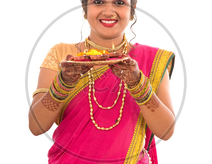 A Traditional Indian Marathi  Woman  Holding Diwali Diyas on an  Pooja Plate   In Hand  and Posing  On an Isolated White Background