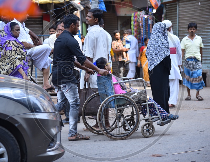 A Young Man Taking Physically Challenged woman In a Wheel Chair to a Polling Station