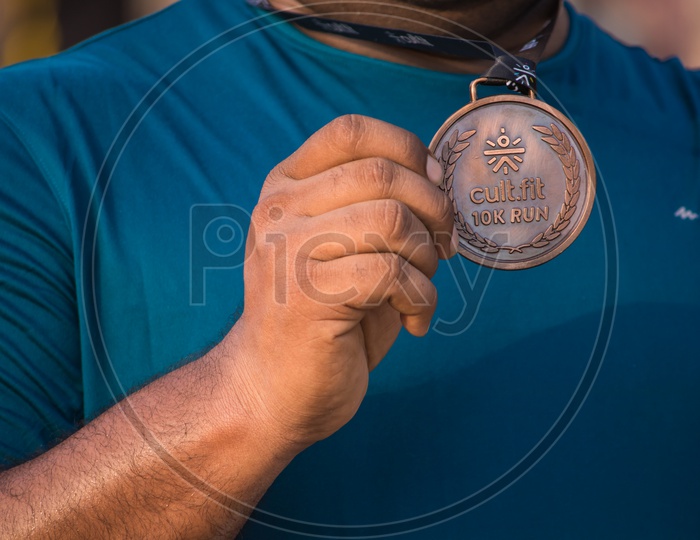 Close-up of athletes hand holding gold medal after victory in stadium