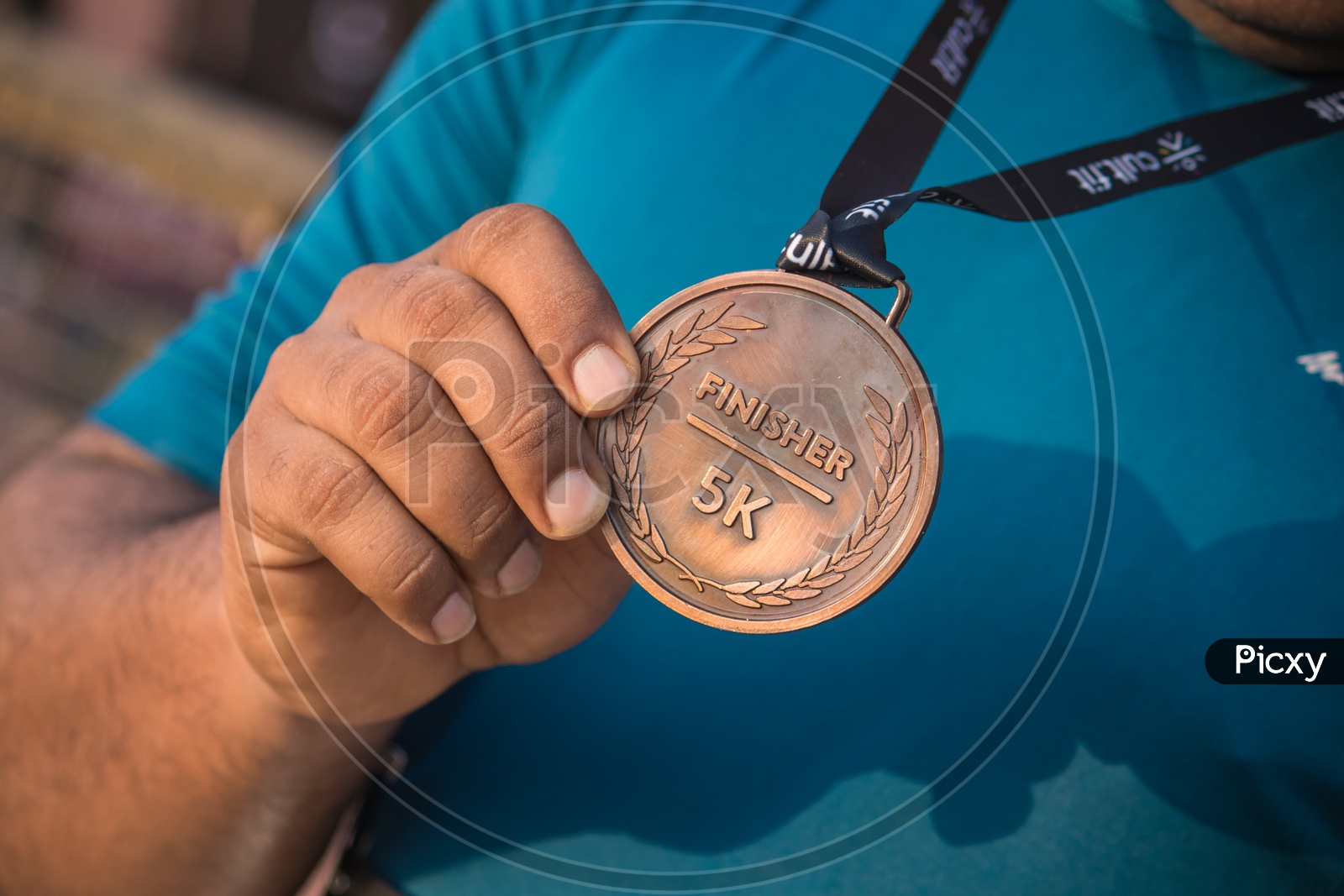 Close-up of athletes hand holding gold medal after victory in stadium