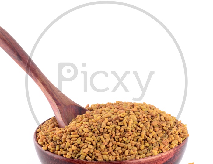 Fenugreek seeds in wooden bowl isolated on white background