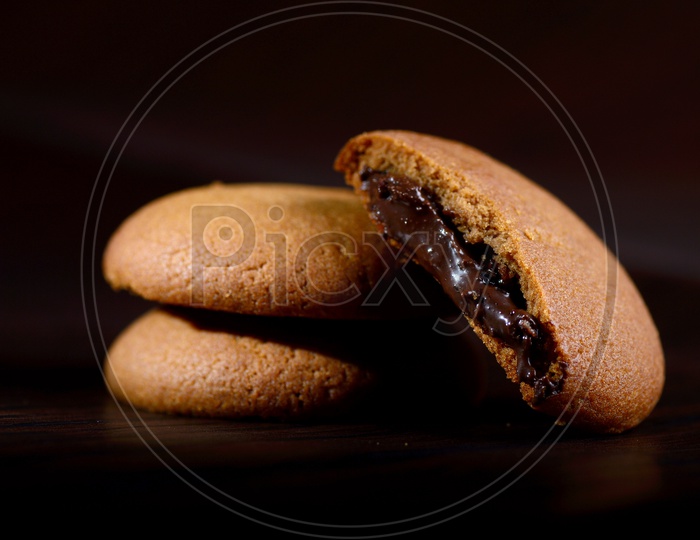 brown chocolate biscuits with cream filling on black background.