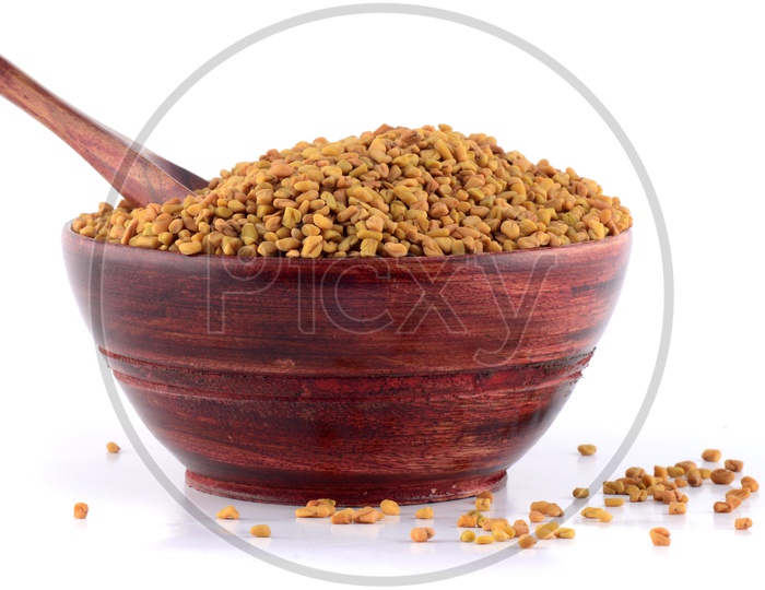 Fenugreek seeds in wooden bowl isolated on white background