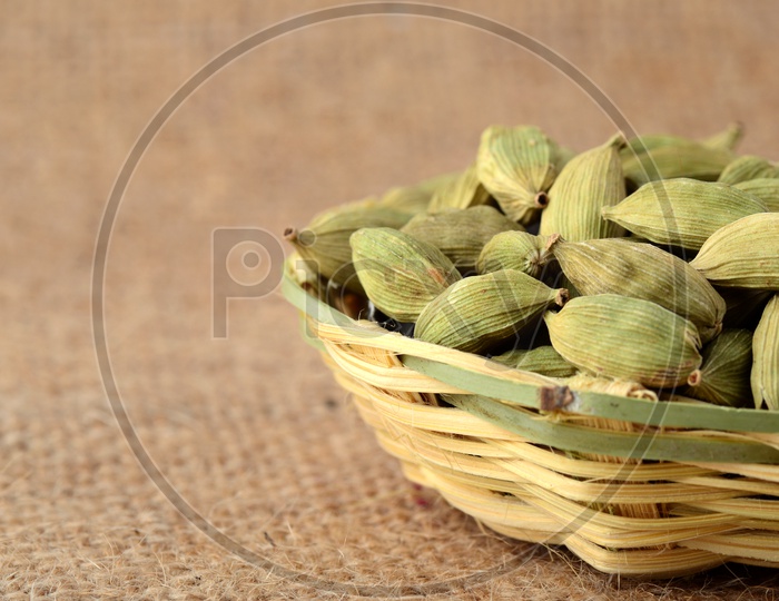 Green Cardamom pods in bamboo basket on sack cloth