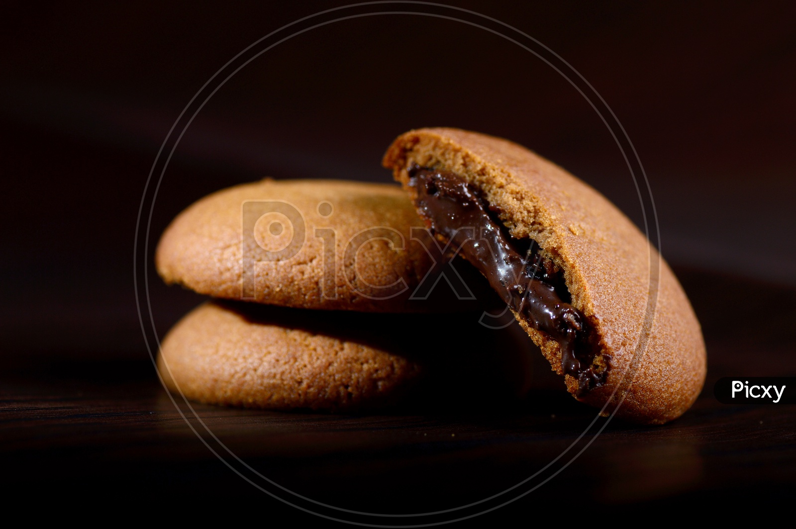 brown chocolate biscuits with cream filling on black background.