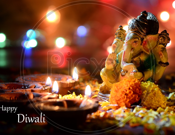 Indian Hindu God , Lord Ganesh Idol with Diwali Clay Diyas and Flowers On an Isolated Background For Ganesh or Diwali Festival Wishes or Greetings Template