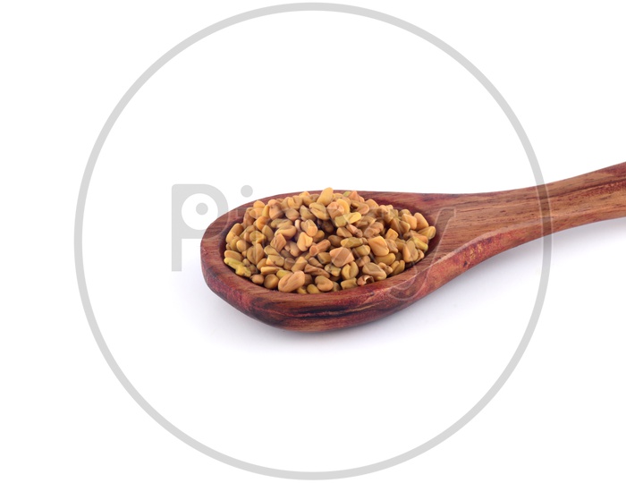 Fenugreek seeds in a wooden spoon isolated on white background