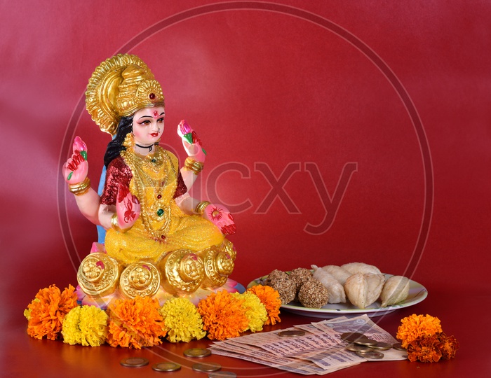Indian Hindu Goddess Lakshmi Idols During Diwali Festival Worships  With Money And  Sweets  on an Isolated Background