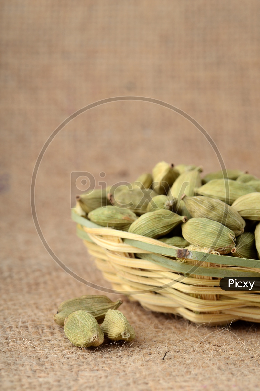 Green Cardamom pods in bamboo basket on sack cloth