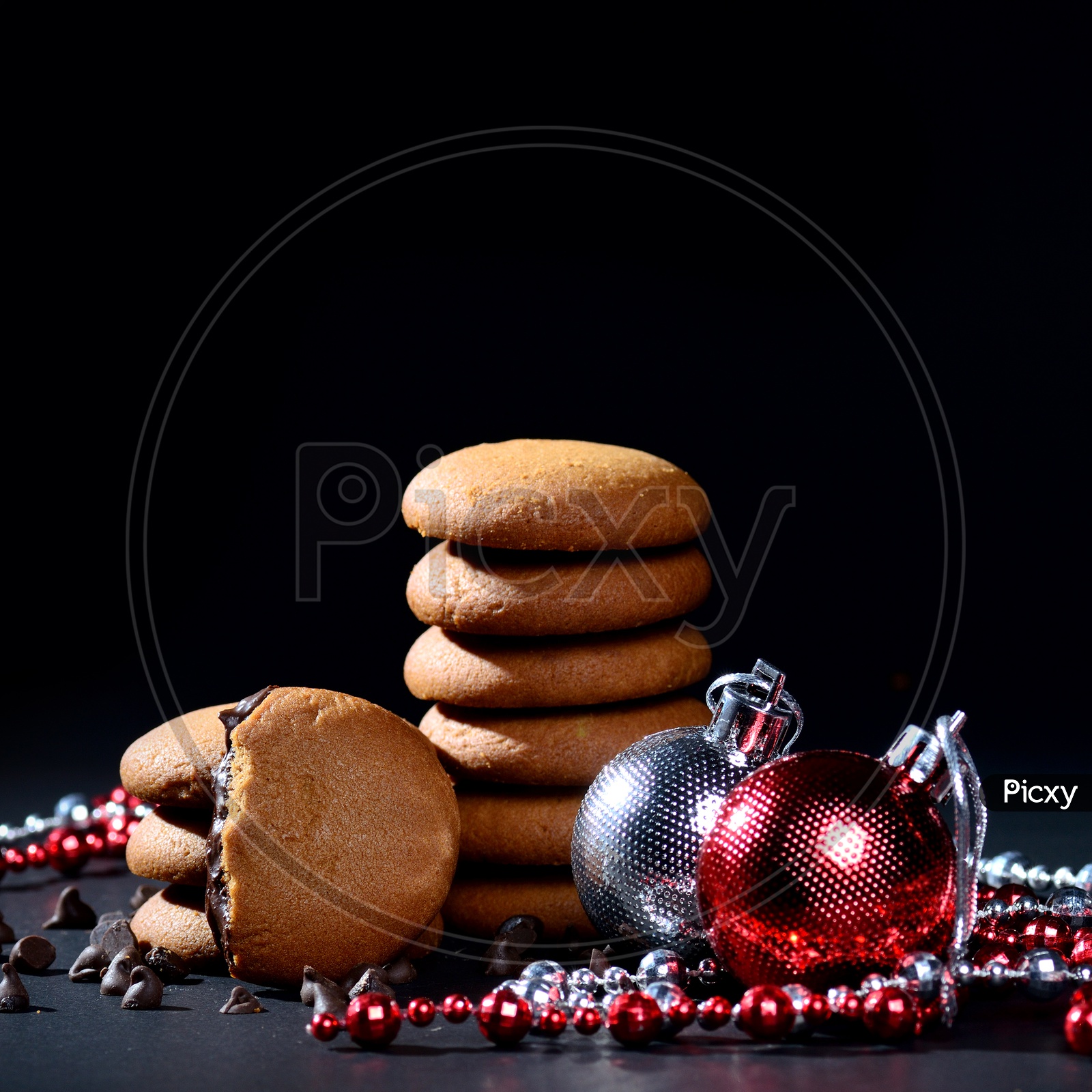BISCUITS - Stack of delicious cream biscuits filled with chocolate cream decorated with Christmas Ornaments on black background
