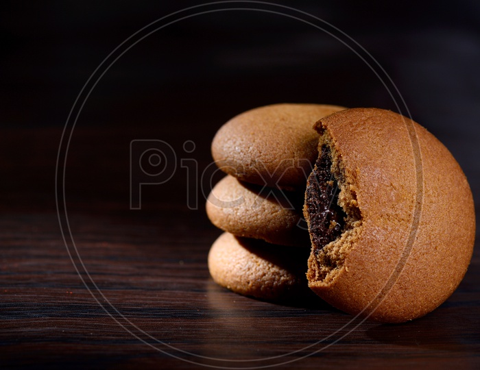 Brown chocolate biscuits with cream filling on black background.