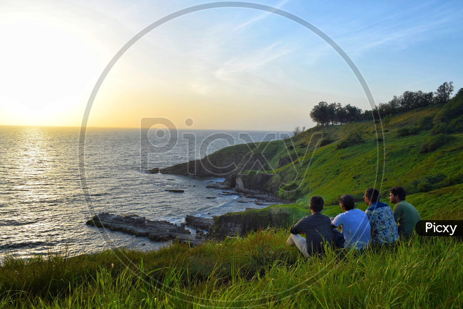 Friends  Watching And Enjoying  The Sunset Over  a  Sea Coast  From a  Hill Top