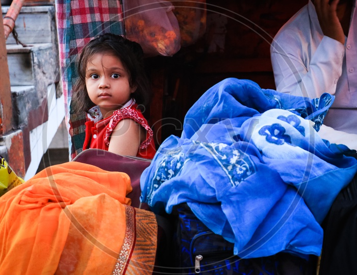 Girl child sitting amidst clothes at a ghat