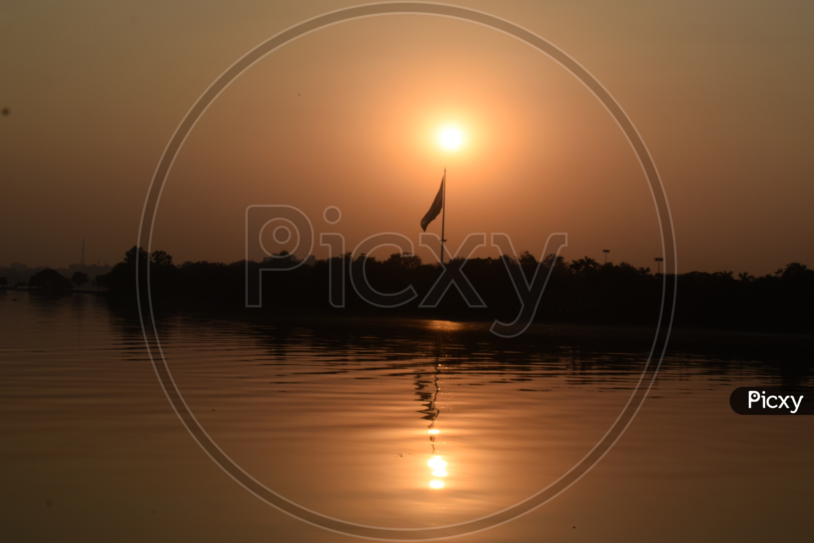 Silhouette Of a Flag Pole  Over a Sunset  And Its Reflection  In Water